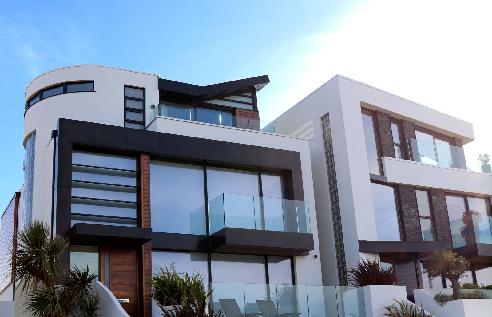 Modern multi-level home with glass balconies against a clear sky